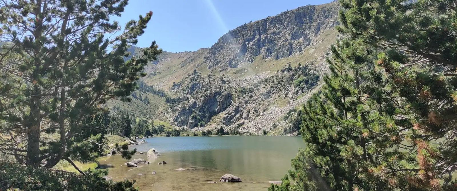 Lac de montagne entre les pins, sous les crêtes